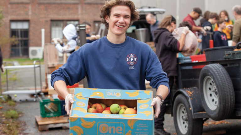 Woodhaven High School Student Volunteer carries a box of apples for the annual cider press