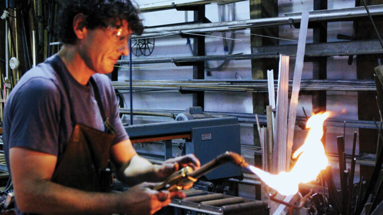 Joey Guerra fine tunes the flame on his torch as he heats up a metal strip