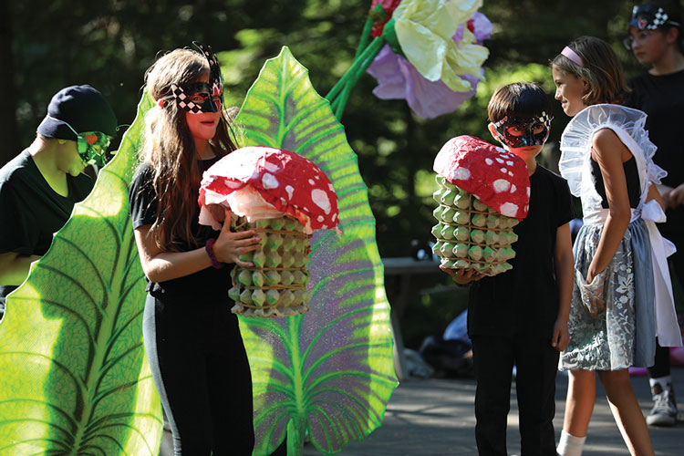 Two young actors holding mushroom props on theatre production