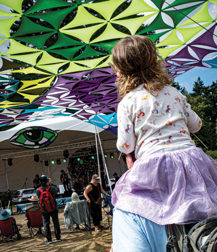 young girl on her father's shoulders under green mandala