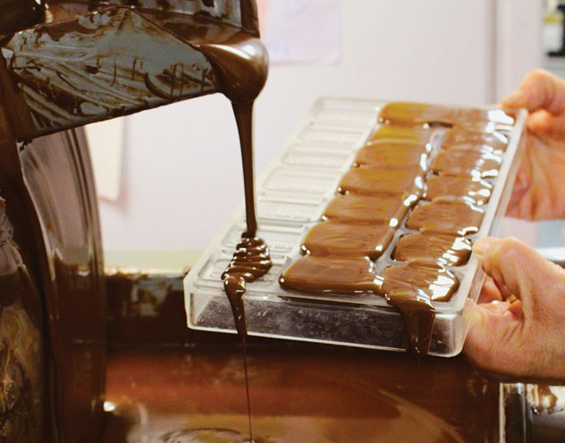 Warm chocolate pours into candy molds