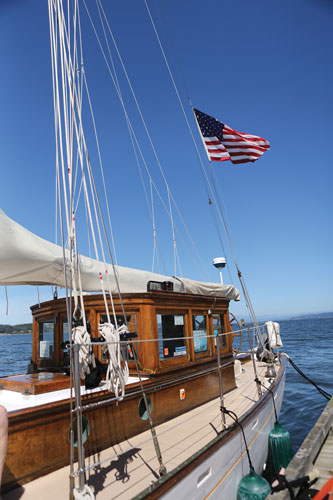 Looking toward the stern of wooden sailboat with U.S. flag flying in the wind
