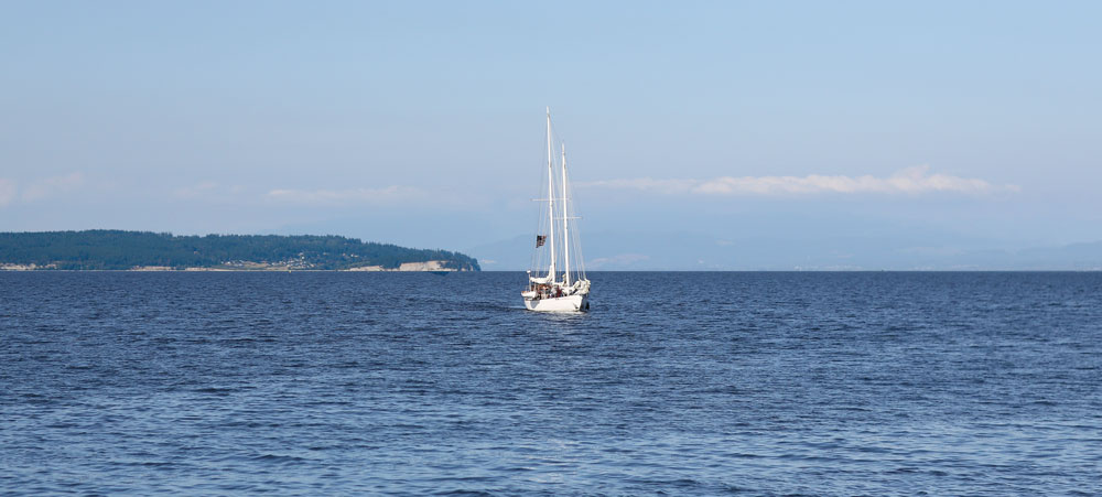 White sailboat sails on a calm day and clear skies