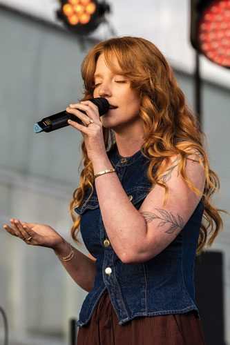 Woman holds a microphone singing with her eyes closed