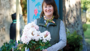 Woman at a nursery holding a flowering rhododendron in a pot