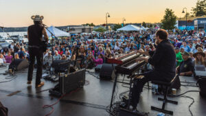 Two performers playing a piano and guitar at an outdoor concert