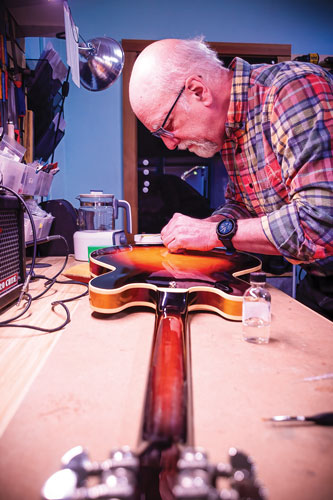 Older man works on the back of an electric guitar