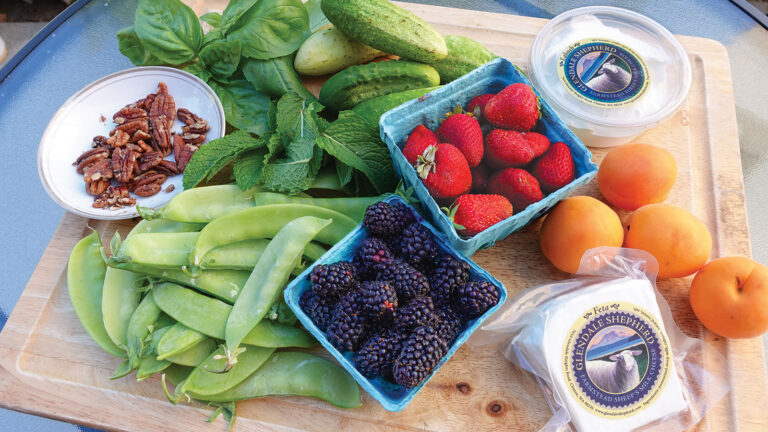 Strawberries, blackberries and assorted greens on a table